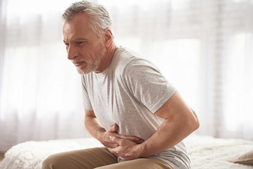 Se muestra adulto mayor con dolor en zona del estomago