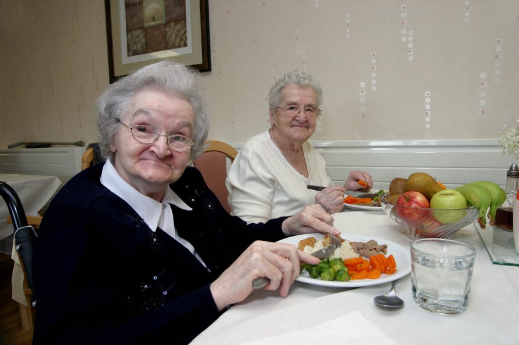 Se muestra a un par de mujeres adultas mayores comiendo ensalada